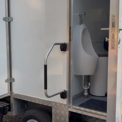 Puerta abierta del baño de varones del tráiler estándar, con urinario