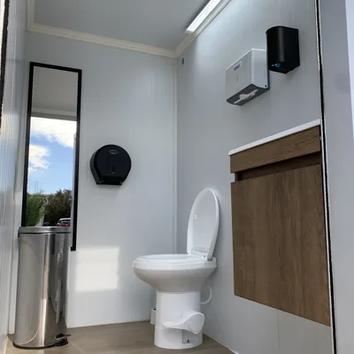 Vista completa de la cabina del baño móvil Maihue: inodoro, vanitorio de madera, espejo e iluminación LED