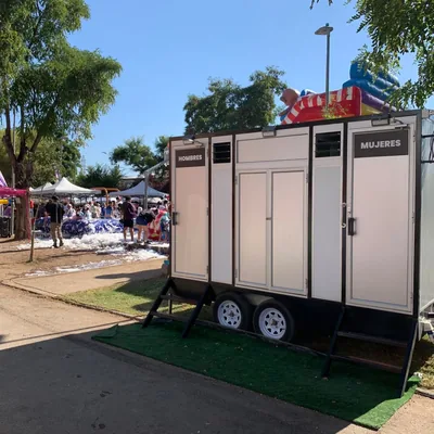 Tráiler de baños móviles Maihue en una feria familiar al aire libre, junto a los juegos inflables