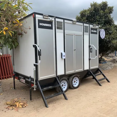 Tráiler de baños móviles Maihue en tres cuartos, con las puertas de hombres y mujeres señalizadas