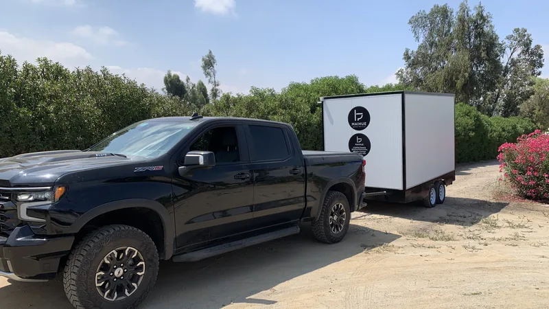 Camioneta remolcando un tráiler de baños móviles Maihue por un camino rural: el traslado va incluido en el arriendo